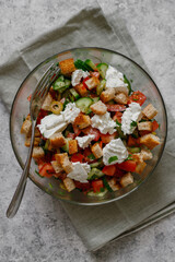 Vegetable salad with cheese and croutons on a light gray background