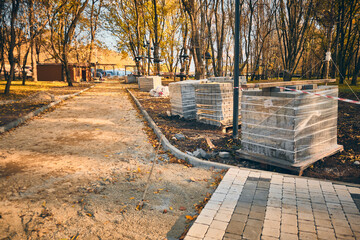 Stacked wooden pallets and laid paving tiles. Public park pavement works. Beautification of park....