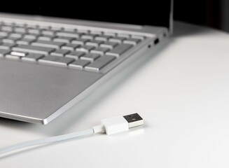 Laptop and white USB cable on table.