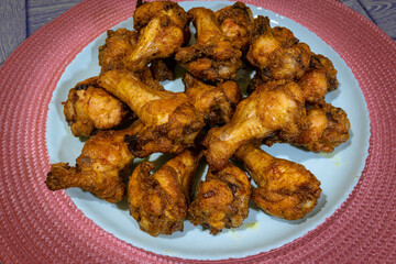 Heap of fried chicken wings on a plate. A full plate of baked chicken wings in spices