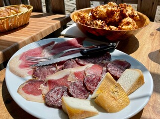 Corsican specialities, crispy golden beignets de fromage, ham, salami sausage and goat cheese served at Bergerie San Bertuli, Monacia-d'Orezza. Castagniccia, Corsica. , 