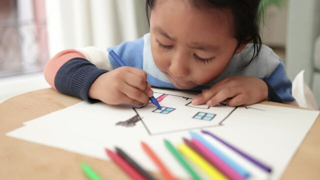 Asian young child boy drawing with crayons indoor at home
