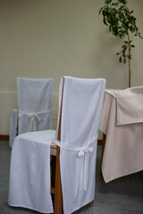 Fototapeta na wymiar Dining chairs with a white fabric protection and a bow