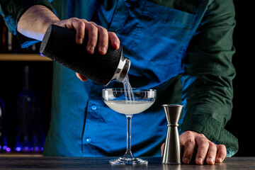 Bartender's hands serving cocktails on bar counter in a restaurant, pub. Mixed drinks. Alcoholic cooler beverage at nightclub on dark background