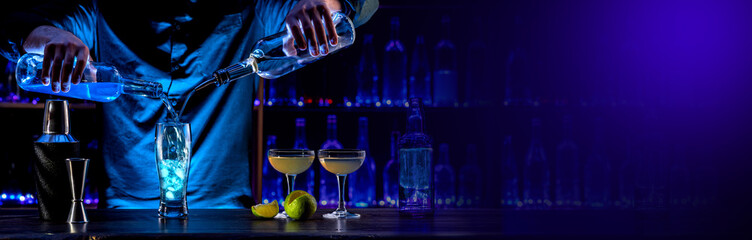 Bartender's hands serving cocktails on bar counter in a restaurant, pub. Mixed drinks. Alcoholic cooler beverage at nightclub on dark background
