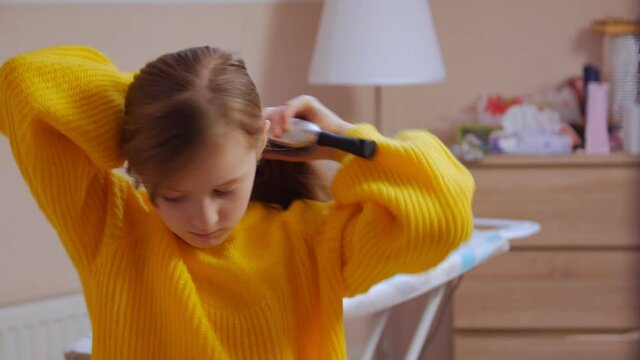 Girl tying her hair in a ponytail closeup