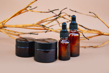 Selective focus. Brown cosmetic bottles on a beige background with wooden decor in the form of...
