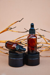 Selective focus. Brown cosmetic bottles on a beige background with wooden decor in the form of branches. The basis for inspiration in cosmetic products. Cosmetic background for product presentation.
