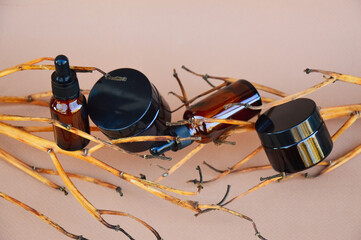Selective focus. Brown cosmetic bottles on a beige background with wooden decor in the form of...