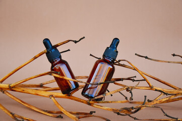 Fototapeta na wymiar Selective focus. Brown cosmetic bottles on a beige background with wooden decor in the form of branches. The basis for inspiration in cosmetic products. Cosmetic background for product presentation.