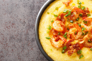 Delicious yellow grits with cheese, shrimps and bacon close-up in a plate on the table. horizontal top view from above
