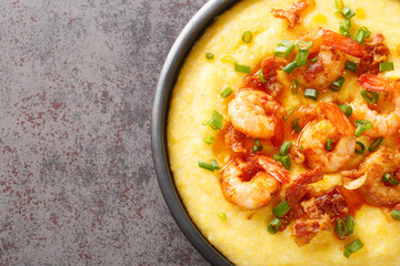 Delicious yellow grits with cheese, shrimps and bacon close-up in a plate on the table. horizontal...