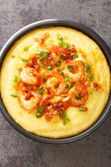 delicious fresh homemade cajun style shrimp and grits with cheddar closeup in the plate on the concrete table. Vertical top view from above