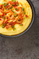Homemade Shrimp and Grits with bacon and Cheddar closeup in the plate on the concrete table. Vertical top view from above