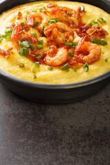 Homemade Shrimp and Grits with bacon and Cheddar closeup in the plate on the concrete table. Vertical