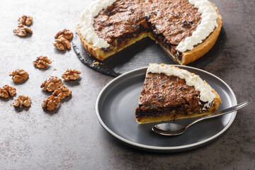 Sliced american chocolate walnuts pie with whipped cream closeup in a plate on the table. horizontal