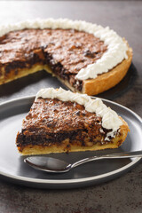 Delicious piece of chocolate walnuts pie with whipped cream close-up in a plate on the table. Vertical