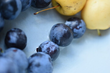 Plums and yellow apples close-up in a plate