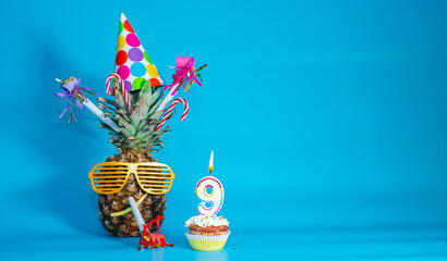 Creative congratulations on nine years for a child. Pineapple with glasses in festive decorations....