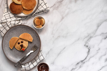 Creative breakfast for children. Funny pancake food art. Banana pancakes in the form of dogs. Copy space. Top view.