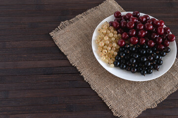 On a white porcelain plate, a berry mix of cherries and currants.