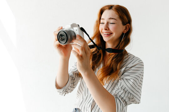 Laughing young woman taking photos with a modern camera, laughing, enjoying the moment