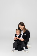 happy mother touching hand of child with down syndrome isolated on grey.