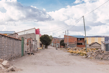 dirt streets and abandoned buildings in the altiplano of bolivia on a sunny day with crices clouds - obrazy, fototapety, plakaty