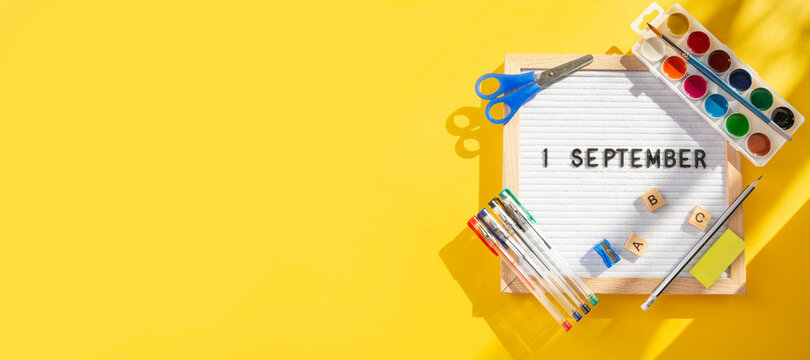 1 september letter board with school supplies as pens, scissors, ABC, paints on yellow background. Education. Knowledge day, study, back to school concept