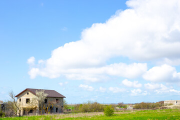 Obraz premium Rural landscape. House under construction in the village and blue sky with clouds on a sunny spring day