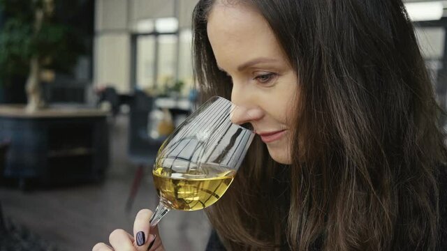 Woman drinking tasting wine in restaurant. Wine expert holding glass of white wine. . Slow motion video.