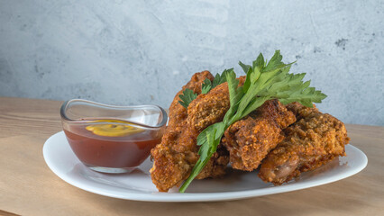 Breaded chicken strips with sauce on white plate. Crispy fried chicken tenders. Fast food on white plate background.