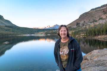 Fototapeta na wymiar Woman in Front of Mountain Scene Reflected in Lake at Yosemite National Park