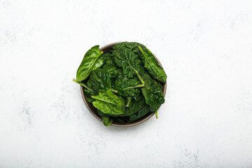 Organic food concept with spinach leaves in a bowl on a white background top view