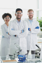 Smiling scientists looking at camera arms crossed in laboratory - obrazy, fototapety, plakaty