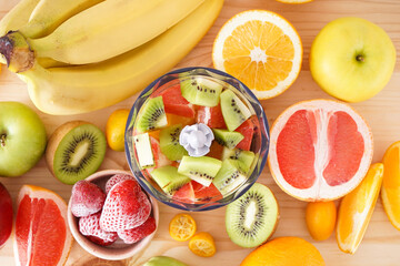 Hand blender and accessories with sliced fruit on a wooden background, flat lay. Close up..