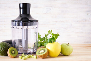 Electrical hand blender with sliced fruit on a wooden background, place for text. Close up.