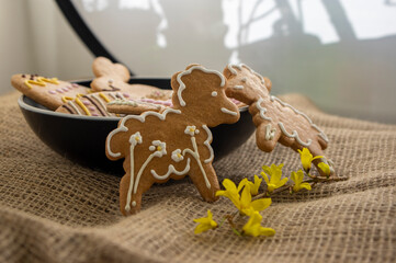 Easter holiday cookies servet on dish on the table with jute tablecloth, group of color painted gingerbread sweets springtime