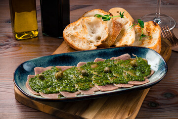 Sliced Beef Tongue Slices on a platter and Dijon mustard on a wooden background