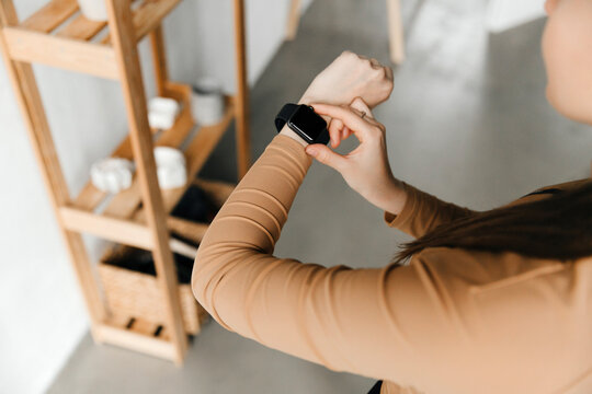 Back view of a young woman checking her calories, looking at her smart watch after a home workout. Counting calories concept