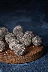 Healthy homemade energy balls on wooden plate. Vegan candies, sweets made of nuts and dates.