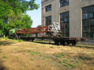 railway crane with a platform under the boom stands on the railway tracks near the locomotive depot 