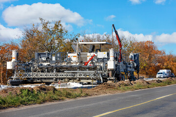 A high performance concrete paver on a new highway construction on a bright autumn day.