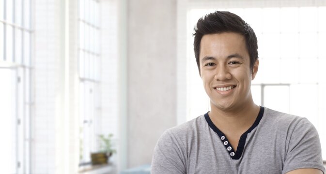 Portrait of happy young asian man at home in 30s, smiling. Copy Space.