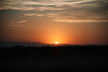 Mountain Sunset with Silhouetted Windmill and Clouds in a Colorful Sky