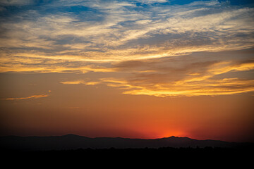 Mountain Sunset with Silhouetted Windmill and Clouds in a Colorful Sky