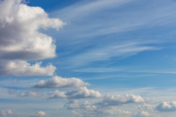 Lush white clouds float in a rhythmic semicircle across the bright blue sky.