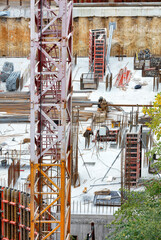 Components of a tower crane on the background of a construction site for the foundation of a modern building with formwork and reinforcement.