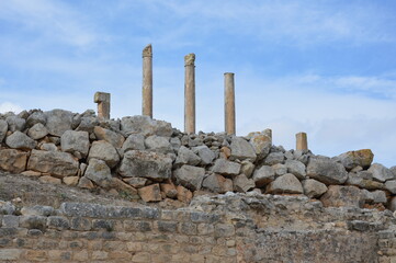 Ruins of  the ancient roman city of Dougga in modern Tunisia, Africa. Blue sky with clouds, white,...