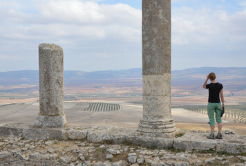 Young girl and the ruins of  the ancient roman city of Dougga in modern Tunisia, Africa. Blue sky...